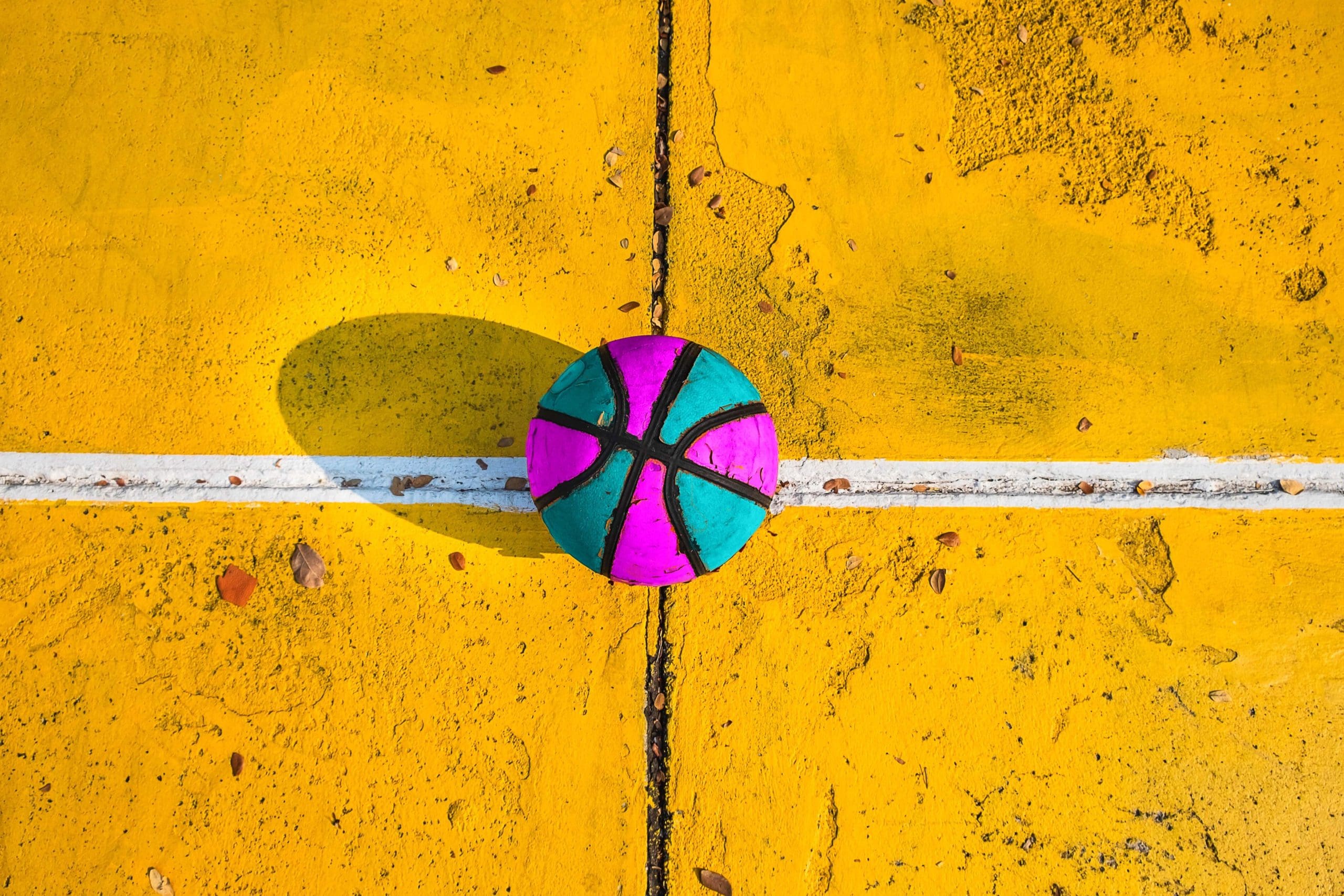 Bright pink and blue basketball on yellow court.