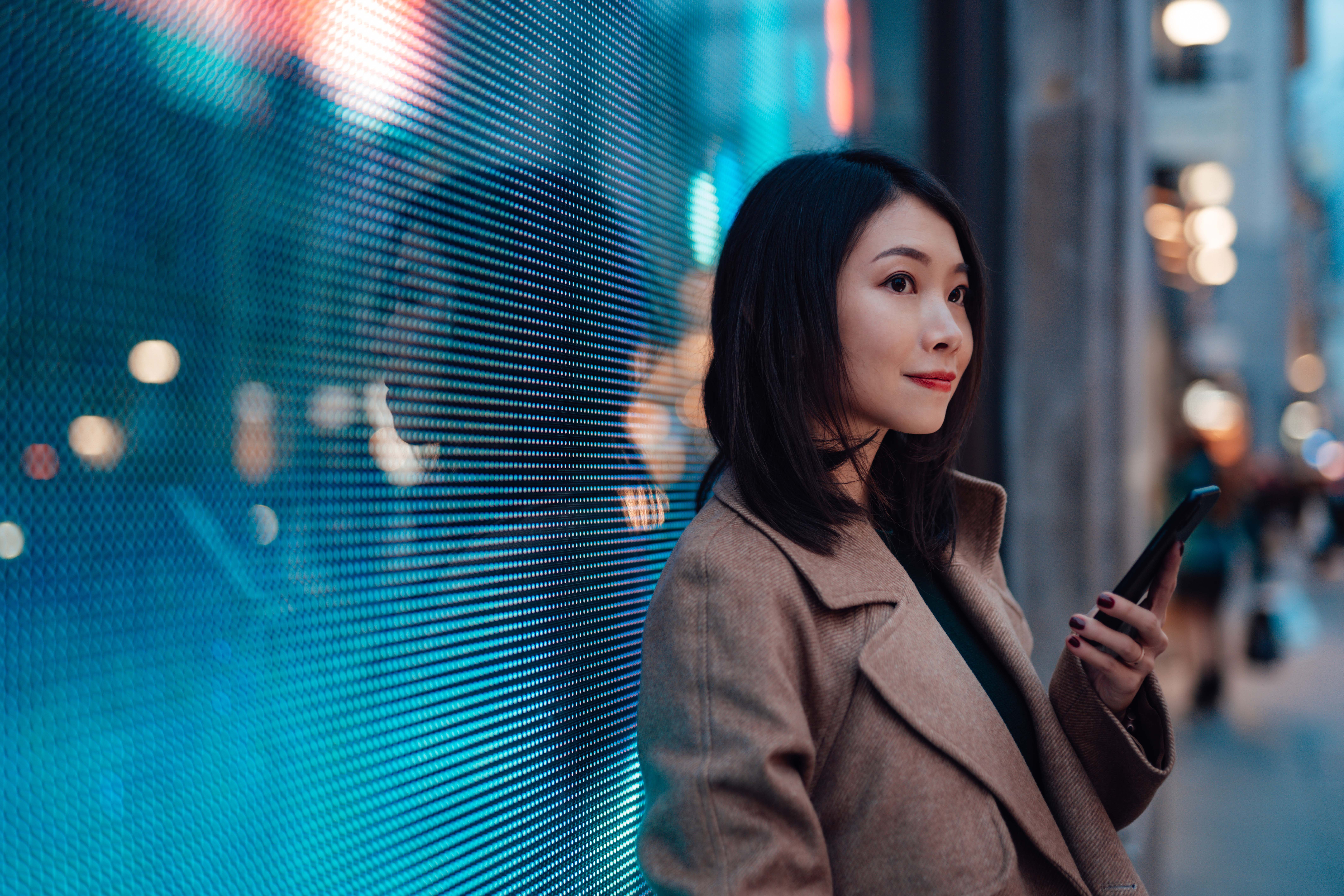 Woman in tan coat holding a cell phone